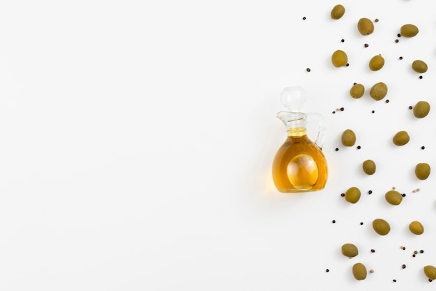 Бутылка оливкового масла с оливками рядом