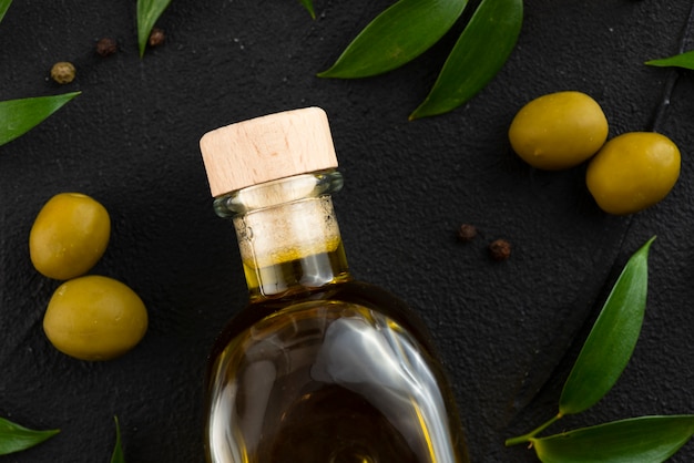 Бутылка оливкового масла с оливками и листьями рядом