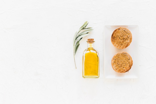 Olive oil bottle with slice of bread on white background