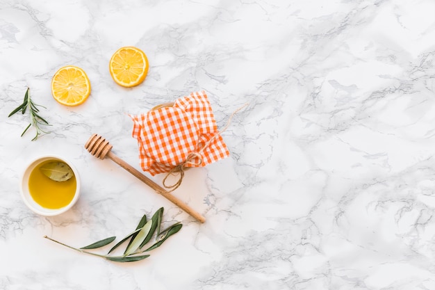 Olive oil bowl, lemon slice, and jar on white background