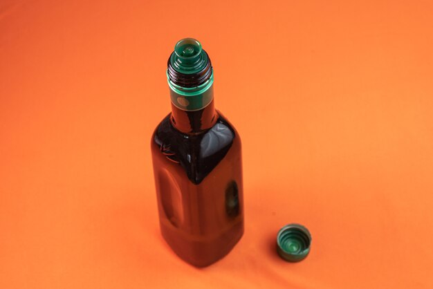 Olive oil container over orange surface