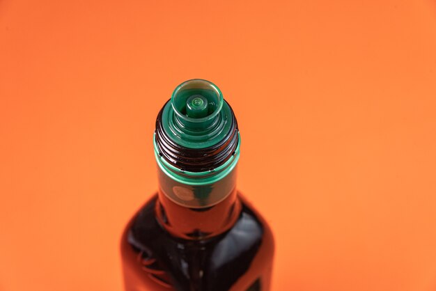 Olive oil container over orange surface