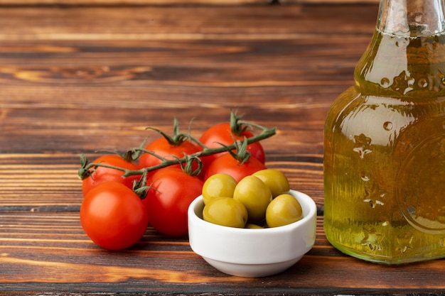 Free photo olive oil olives and tomatoes on wooden background