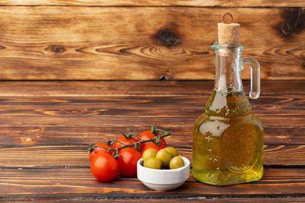 Olive oil olives and tomatoes on wooden background