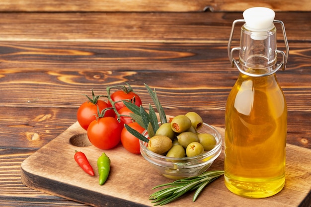 Olive oil olives and tomatoes on wooden background