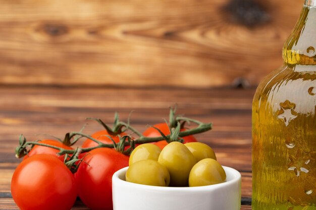 Olive oil olives and tomatoes on wooden background