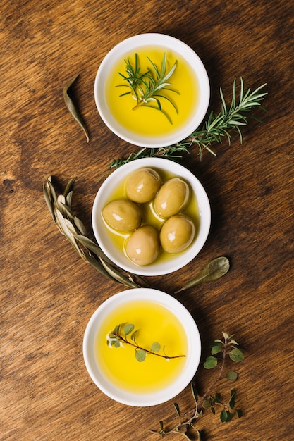 Olive and oil with rosemary arranged bowls top view