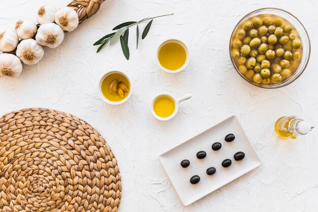 Olive and oils with bunch of garlic bulbs and coaster on white background