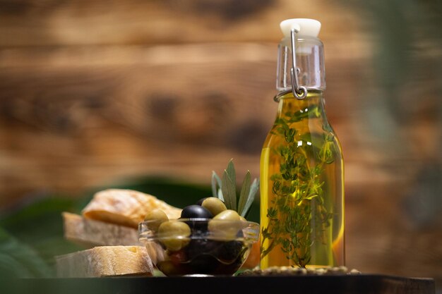 Olives and bottle of olive oil on wooden background