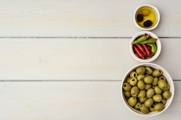 Olives in a bowl on wooden background top view