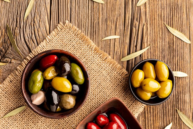 Olives in bowls and leaves on textile material