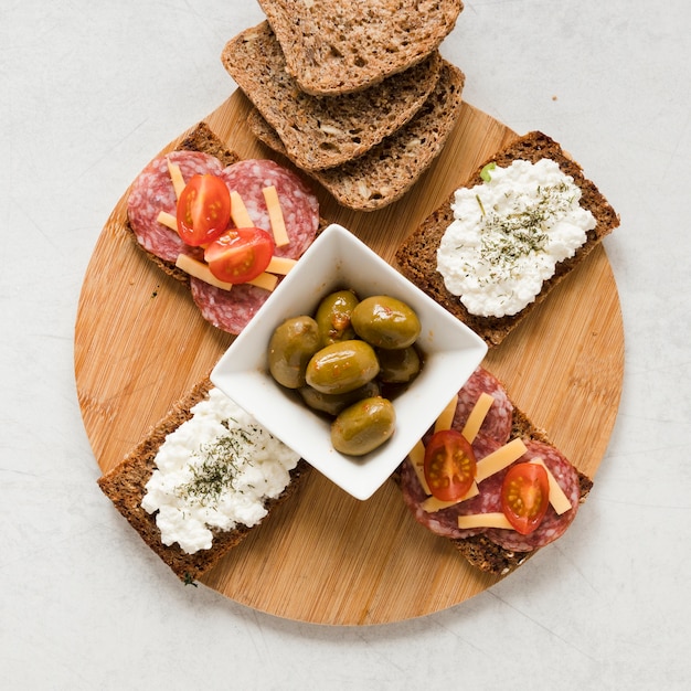 Olives and sandwiches on cutting board