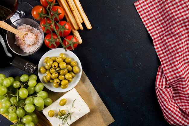 Foto gratuita olive, pomodori e uva sulla superficie scura