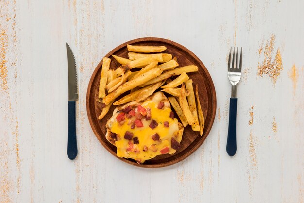 Omelette and french fries on wooden board on grunge painted desk 