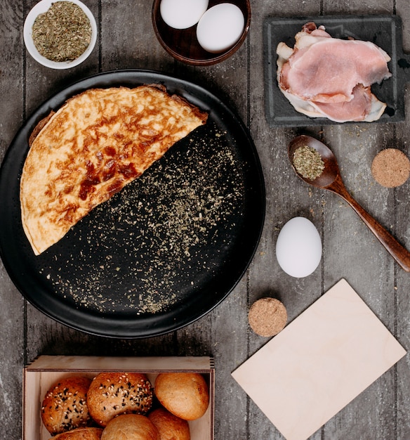 Omelette in pan and side raw bacons