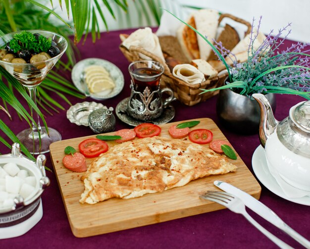 Omelette platter with sausage and tomatoes, served with tea, olive, bread and lemon