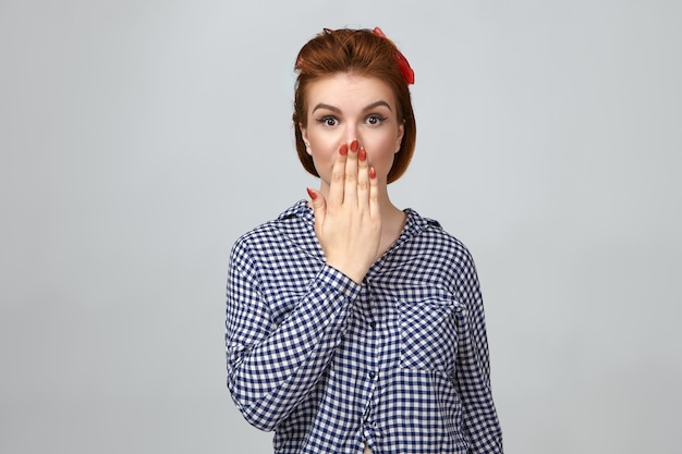 Omg. Cute girl expressing full disbelief, covering mouth. Picture of astonished beautiful young woman keeping hand on her lips