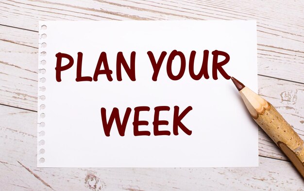 明るい木製の背景に、色鉛筆と白い紙に「plan yourweek」というテキストが表示されます Premium写真