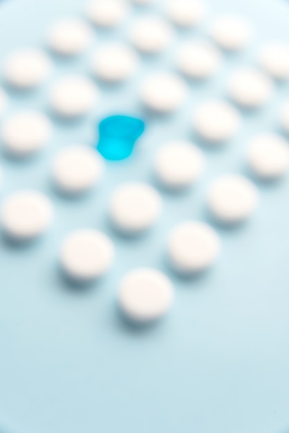 Free photo one blue liquid capsule in a grid of white tablets