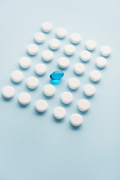 白い錠剤のグリッドに1つの青い液体カプセル