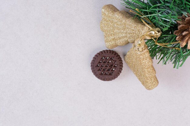 白いテーブルの上のクリスマスのおもちゃと1つのチョコレートクッキー。