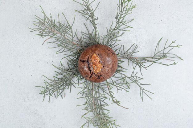 One chocolate cookie with walnut on white surface.