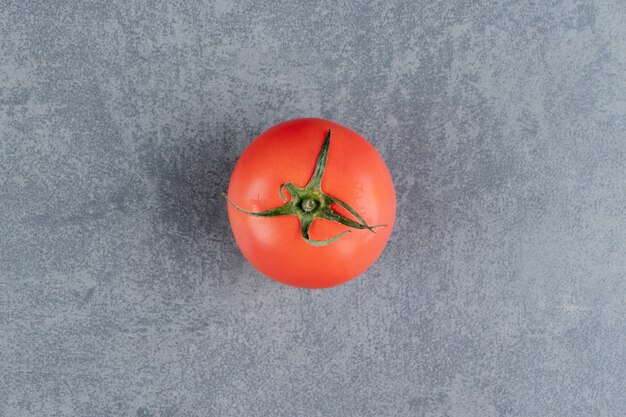 Один свежий красный помидор на мраморной поверхности
