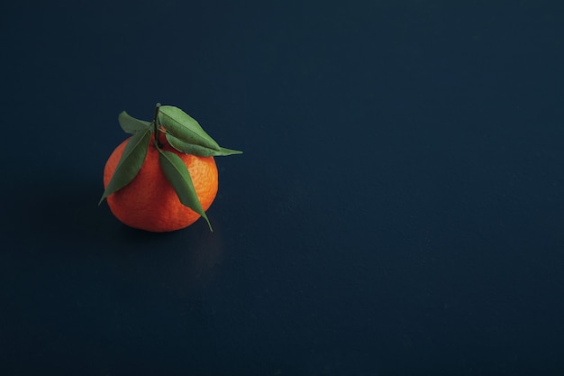 One fresh ripe tangerine isolated on old wooden rustic table painted in blue color