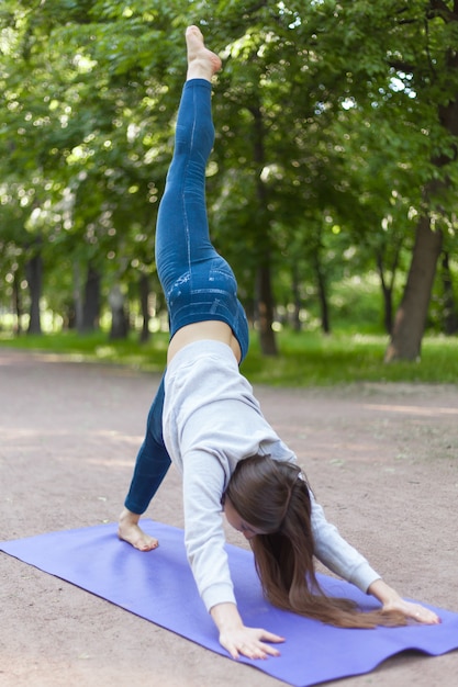 Foto gratuita una gamba giù cane posa yoga nel parco vicolo