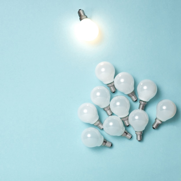 Одна лампочка выдающаяся, светящаяся по-разному. Идеи бизнес творчества концепции.