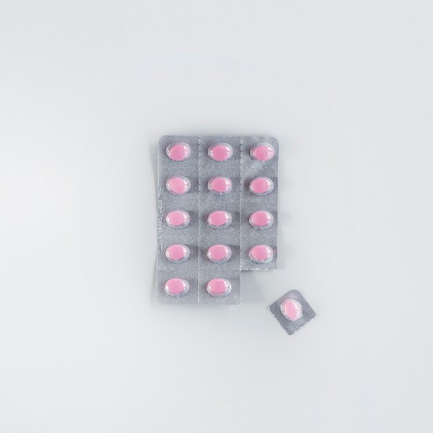 One pink pill cut from the blister over the white background