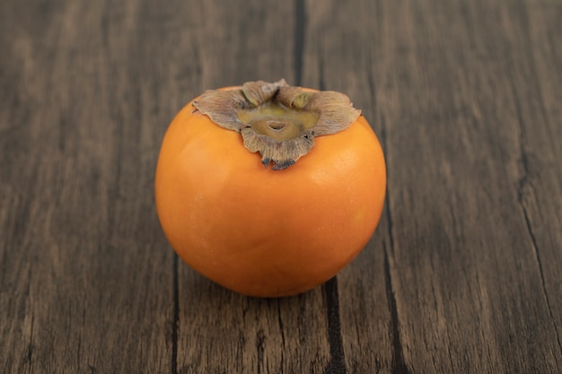 Un frutto di cachi maturo posto su una superficie di legno