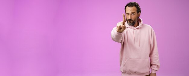 하나의 규칙은 분홍색 후드티를 입은 진지한 모습의 강력하고 집중된 결정적인 성인 수염 난 남성을 경청합니다.