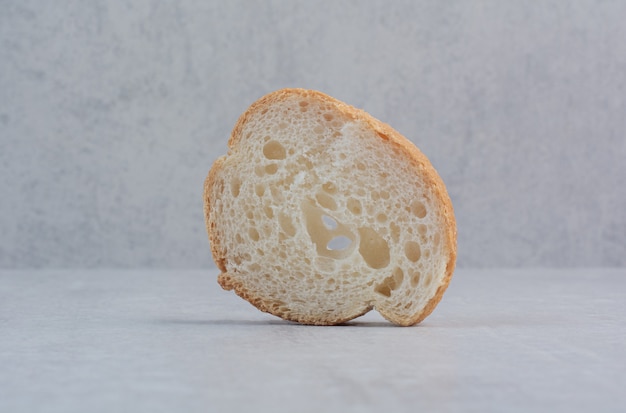 One slice of round fresh white bread on marble background. 