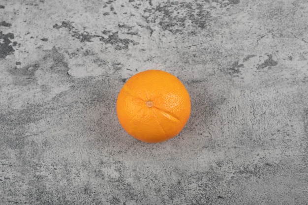 One whole fresh healthy orange fruit on stone table.