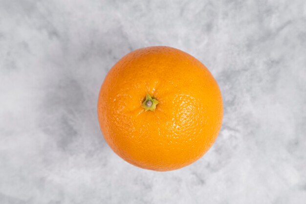 One whole fresh juicy orange fruit placed on marble