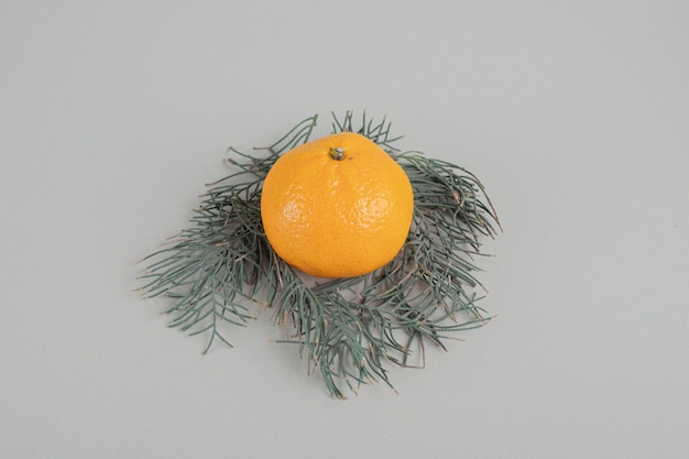 Free photo one whole fresh tangerine on a gray background.