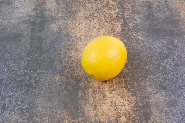 Один целый лимон на каменной поверхности