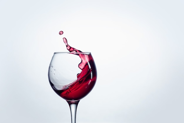 The one wine glass with red wine against white