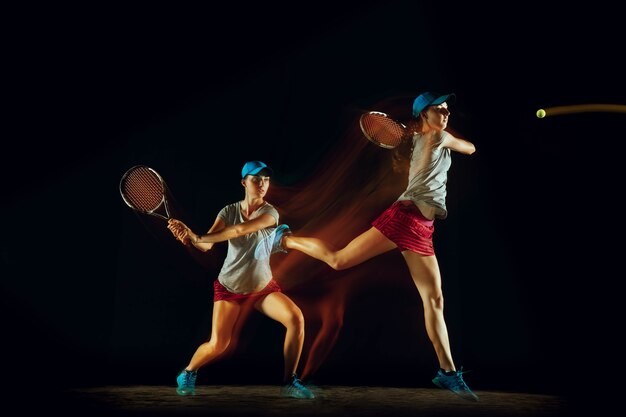 One woman playing tennis in different positions isolated on black wall in mixed and stobe light