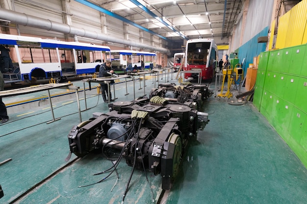 One working day of modern automatic bus manufacturing with unfinished cars automotive parts workers in protective uniform on manufacturing background