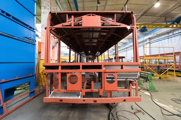 One working day of modern automatic bus trolleybus car production with unfinished cars workers in protective uniform in factory background automobile assembly line welding arm