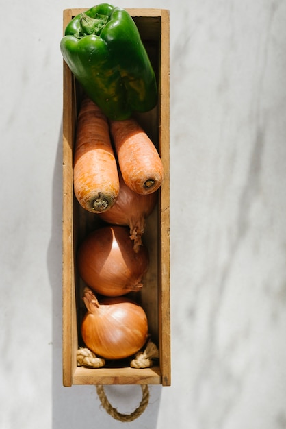 Onion; carrot and green bell pepper in wooden tray