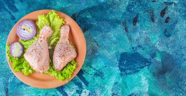 Free photo onion lettuce leaves and chicken drumstick on a clay plate