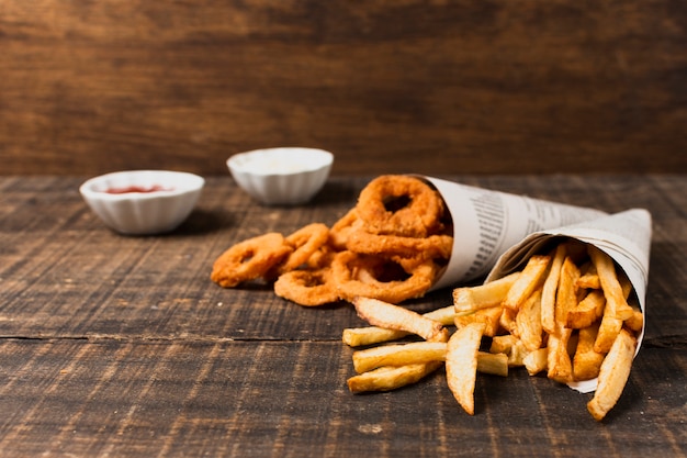 Onion rings and fries on wooden table