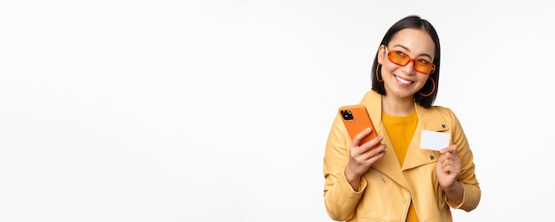 온라인 쇼핑 및 배달 개념 신용카드와 sm을 들고 세련된 옷을 입은 행복한 한국 소녀
