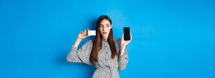 Free Photo online shopping pensive lady in dress showing empty phone screen and plastic credit card order in in