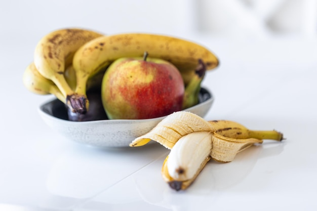 Foto gratuita una banana aperta e un piatto di frutta sul tavolo della cucina