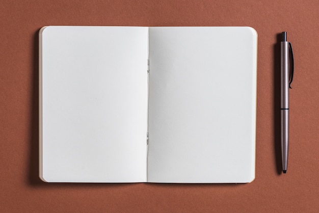 Open blank book with pen on brown background