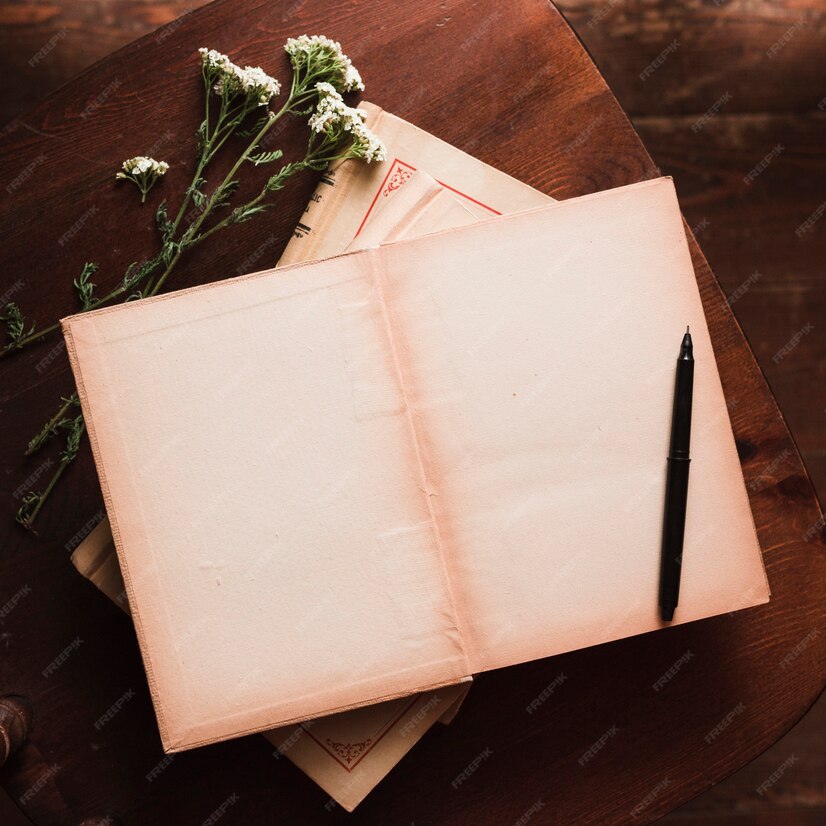 Open book with pen on top of closed book, white flowers with long stems under left side of open book.